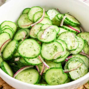 Close up view of Cucumber Dill Salad with red onion in a white bowl.