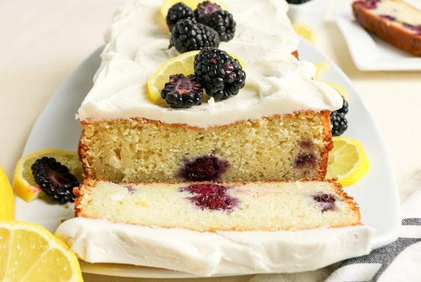 Front view of lemon blackberry loaf with a slice cut off on a plate.