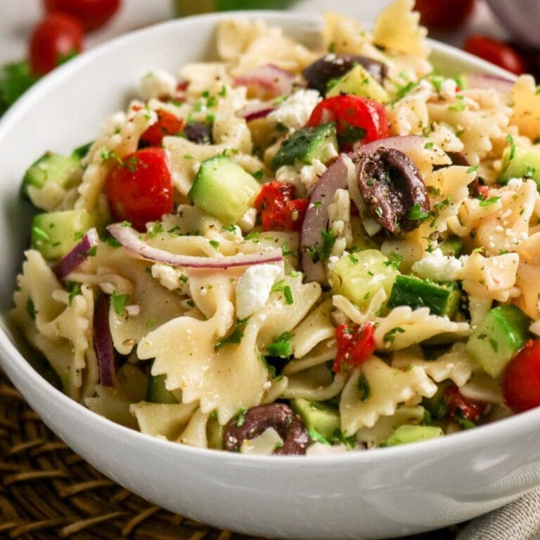 Closeup view of a white serving bowl filled with Mediterranean Pasta Salad.
