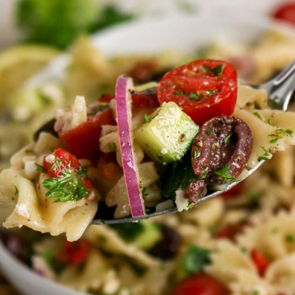 Close up view of a forkful of the best Mediterranean pasta salad.