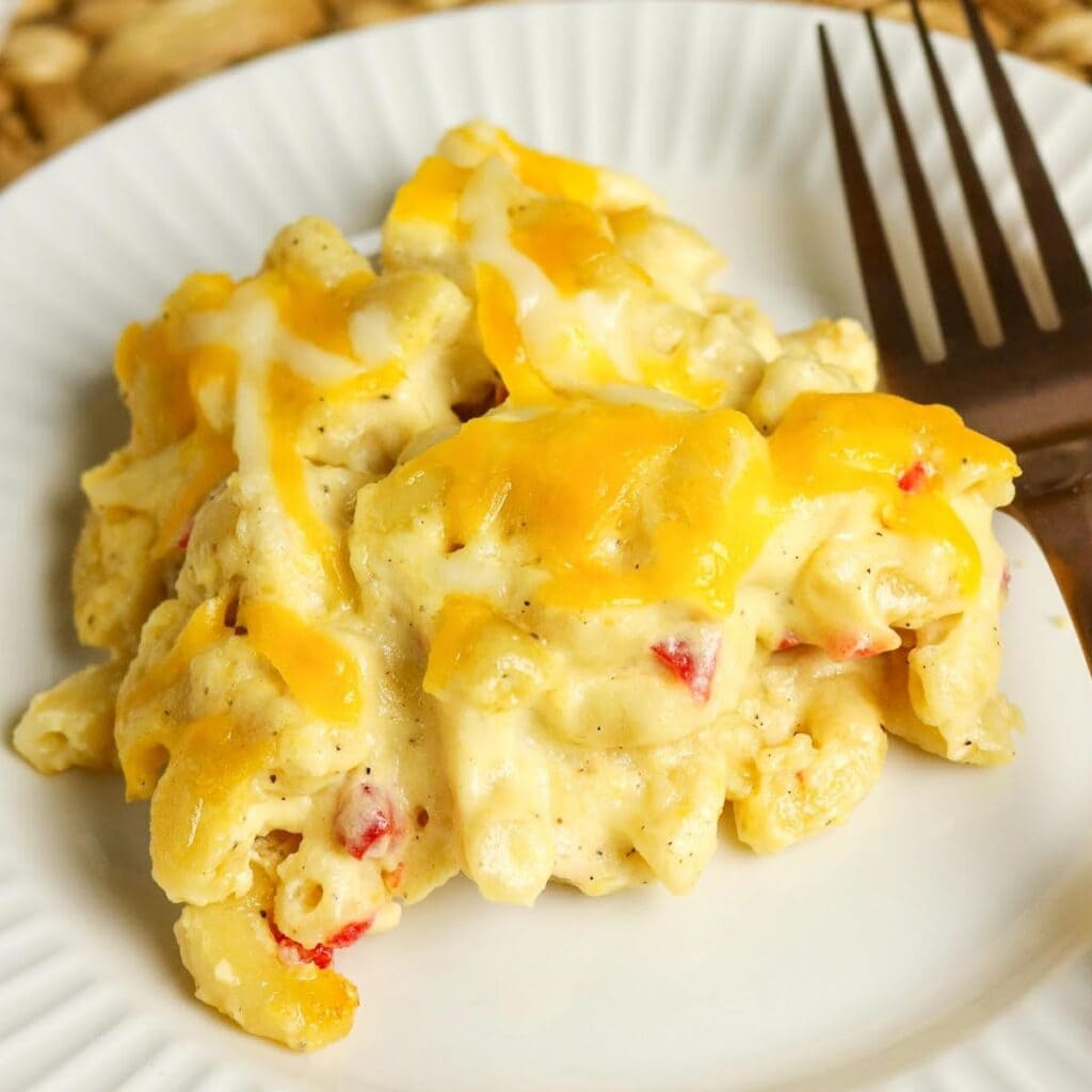 Scoop of Pimento Mac and Cheese on a white plate with a fork.