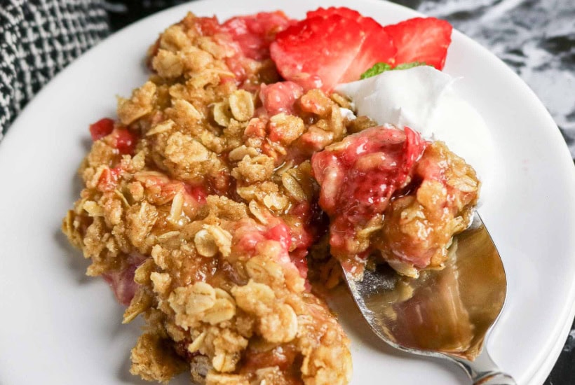 Spoon scooping up a bite of strawberry crumble.