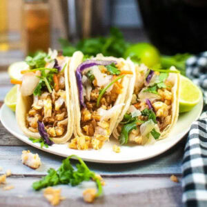Three air fried fish tacos on a white plate.