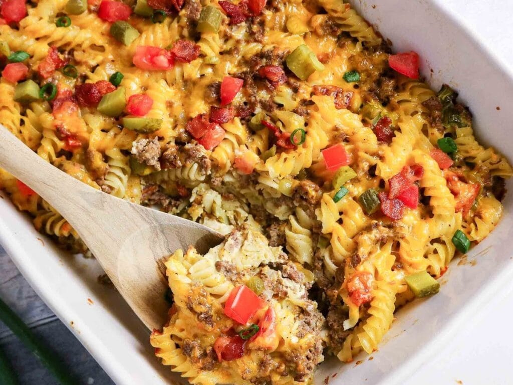 Casserole dish of bacon cheeseburger hot dish with a wooden serving spoon in it.