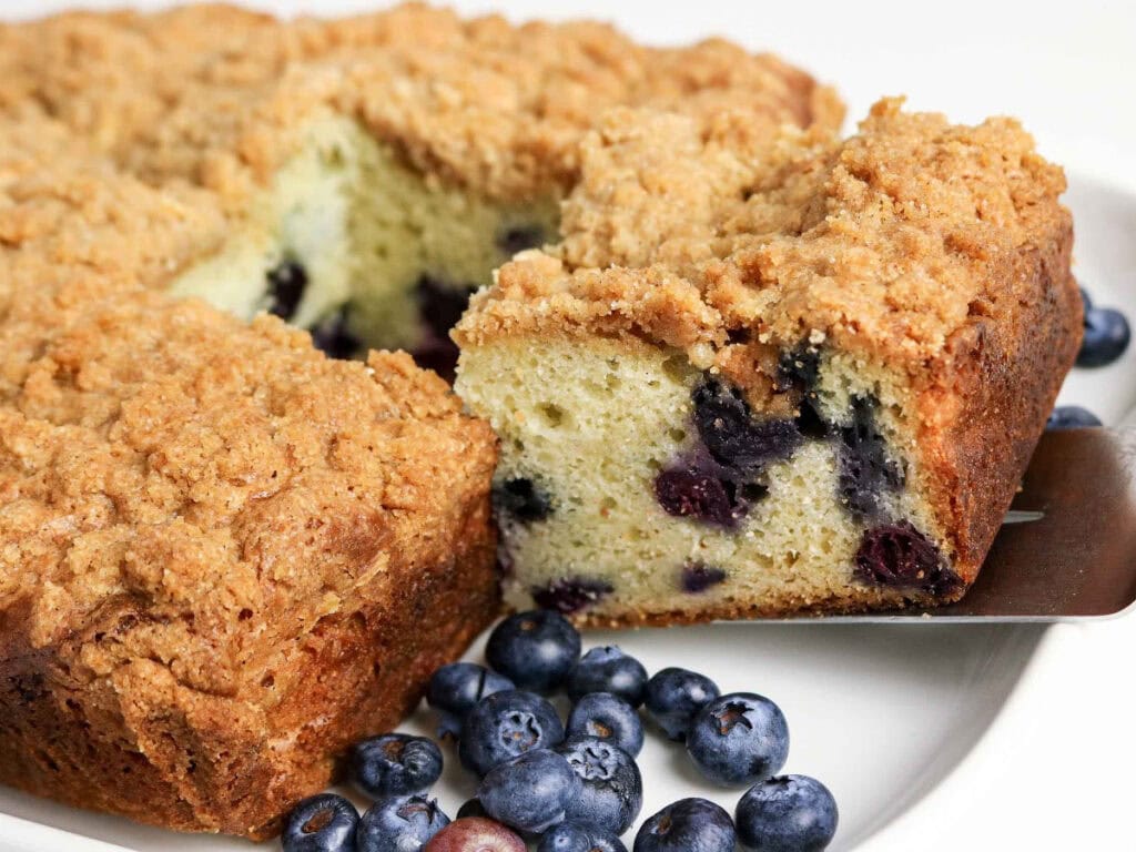 Close up of a slice of sour cream blueberry coffee cake being removed from the pan.
