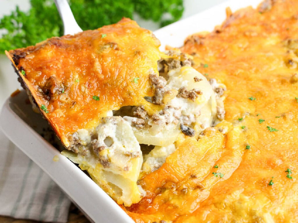Scooping out a slice of hamburger potato casserole from the dish.