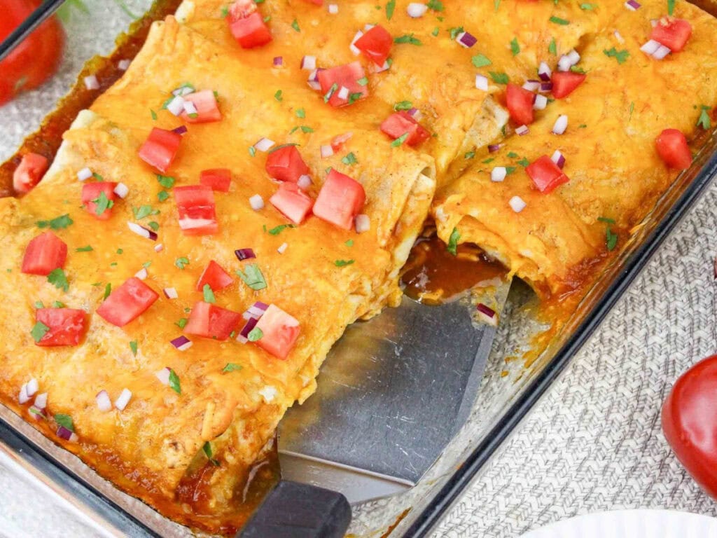 Overhead view of burrito breakfast casserole recipe in a clear white casserole dish with a piece taken out.