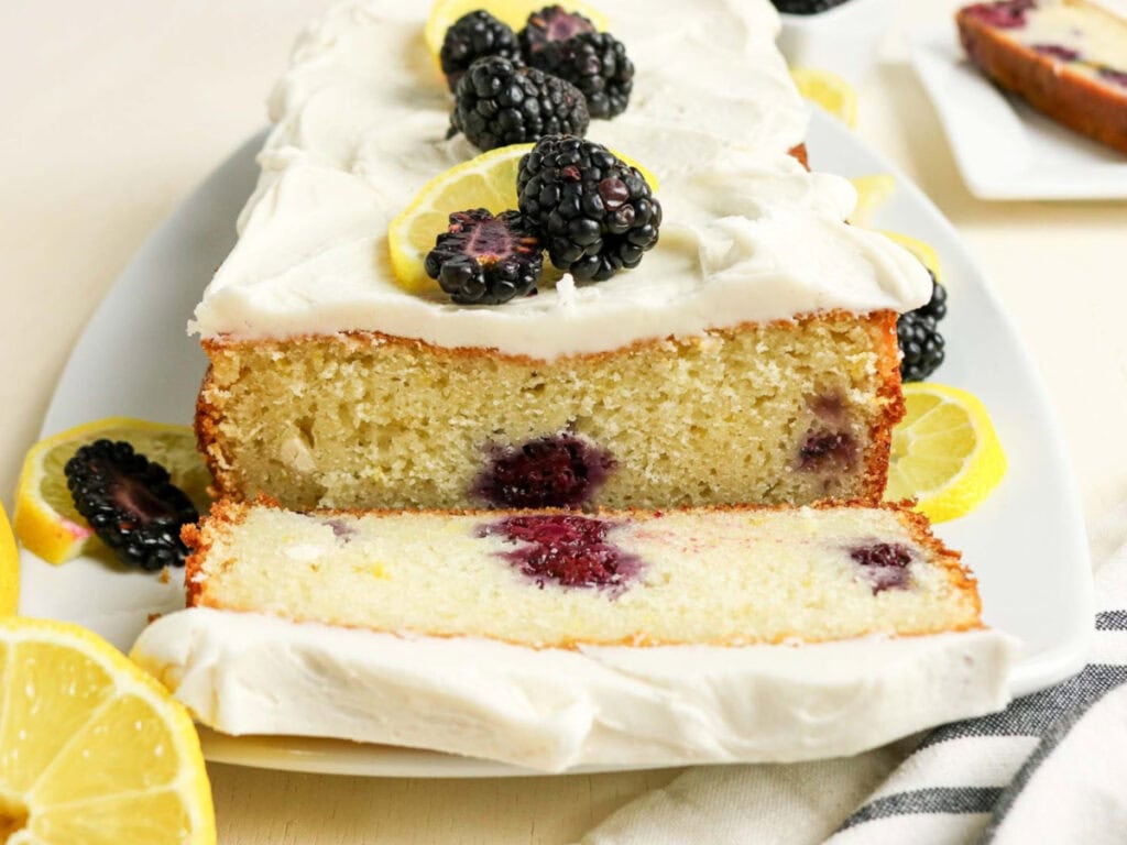 Front view of lemon blackberry loaf with a slice cut off on a plate.