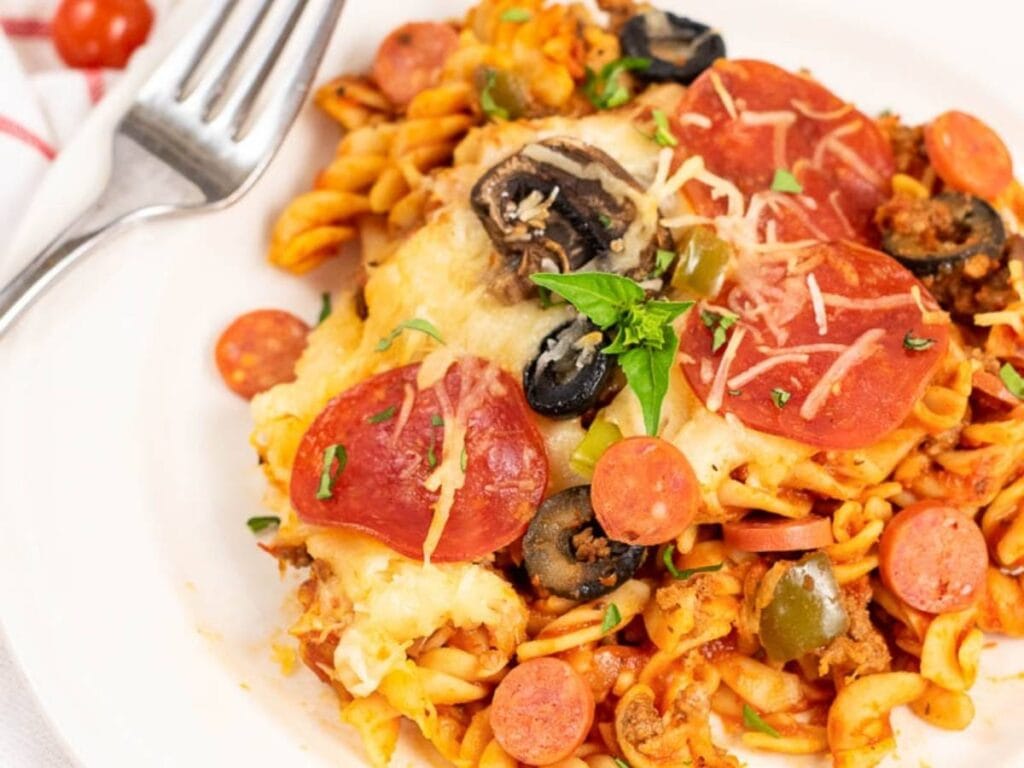 Baked pizza pasta on a white plate with a fork.