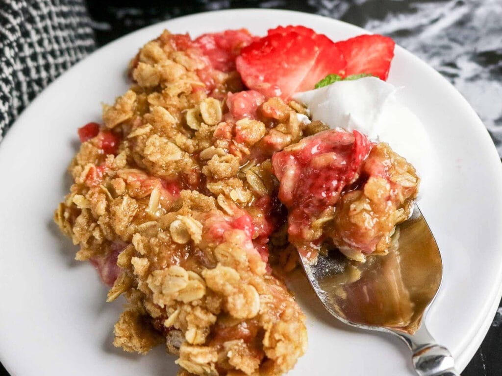 Spoon scooping up a bite of strawberry crumble.