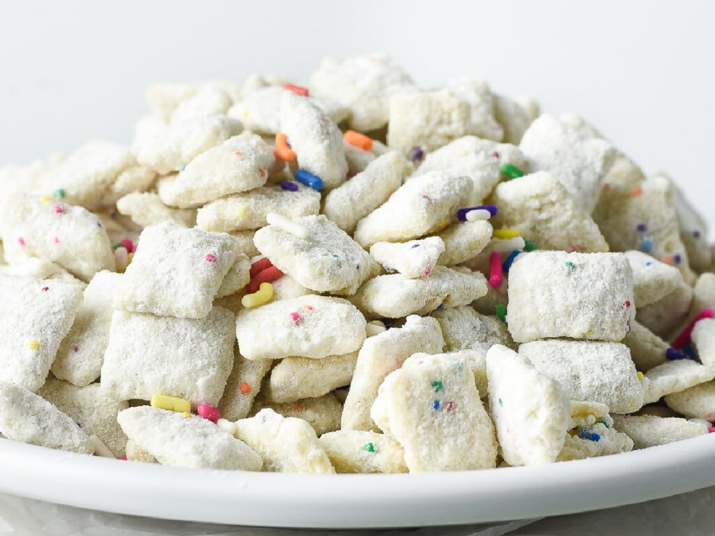 Front view of a bowl of cake batter puppy chow with cake mix.