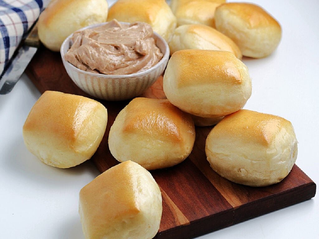 A batch of Texas Roadhouse rolls made from scratch on a cutting board with signature butter.