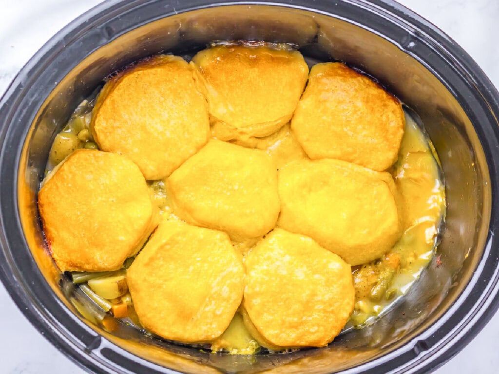 Overhead view of chicken pot pie topped with biscuits in the crockpot.