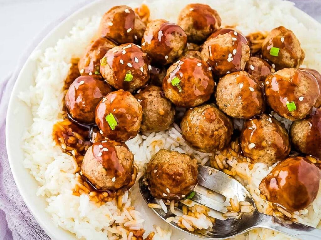 White dish of Teriyaki Meatball Rice Bowl with a serving spoon.